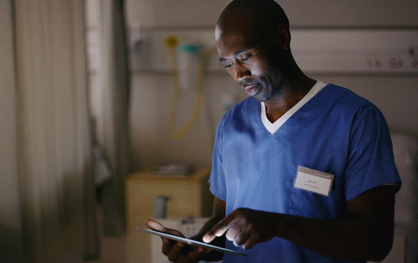 Фото медицинского работника, который смотрит карту пациента, пользуясь планшетом