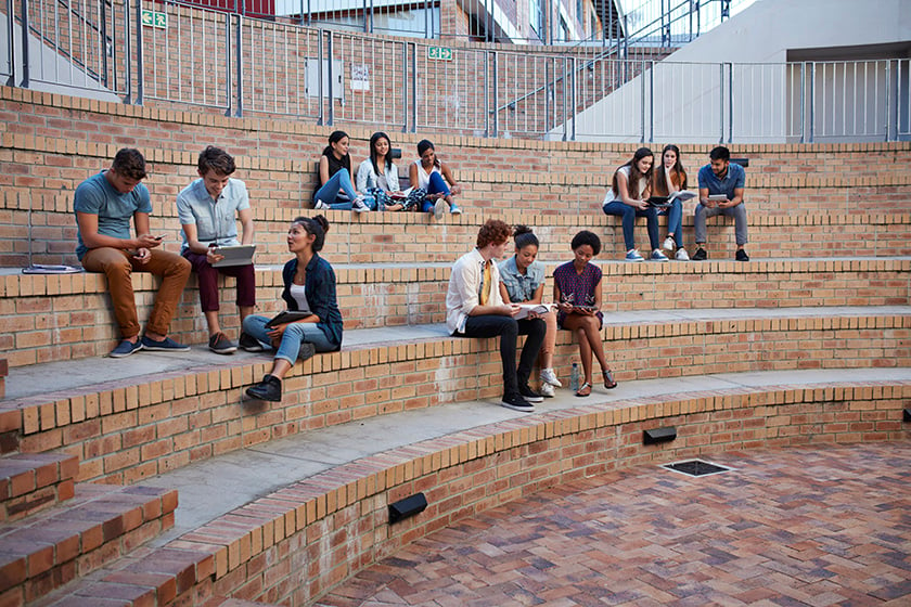 Студенты занимаются в группах на открытом воздухе на территории кампуса