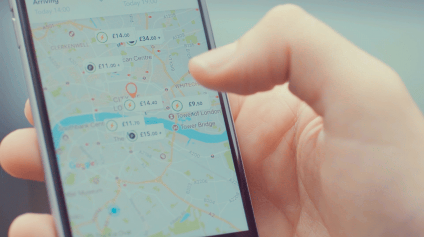 Рука с мобильным телефоном, в котором открыта карта через приложение JustPark